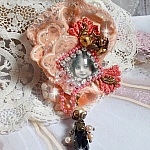 Broche Rustic Rose crée avec un cabochon représentant une jeune fille souriante, de la dentelle Orange strassé et Rose, des cristaux, des perles en verre et des accessoires divers