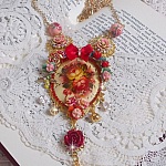 Collier Roseraie Provençale crée avec des perles en verre, céramique, résine, des accessoires en plaqué Or et autres avec un nœud en satin Rouge